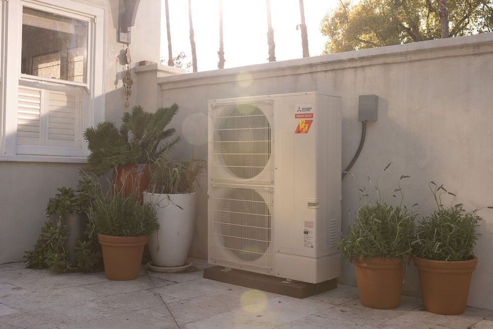 A Mitsubishi outdoor unit beside a warm comfortable home