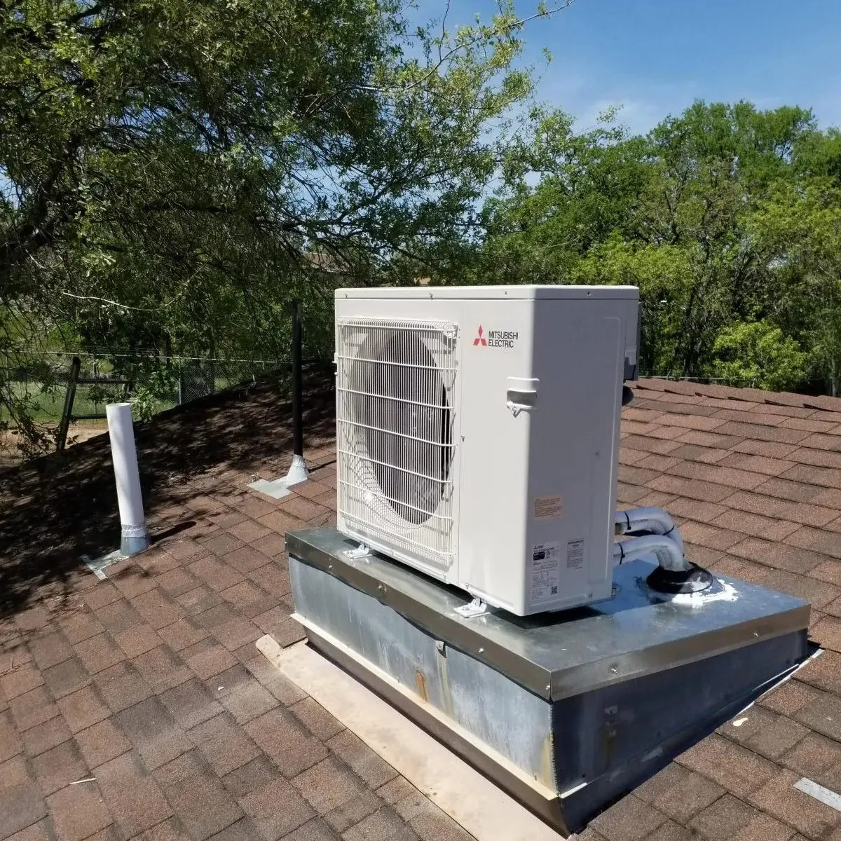 A roof mounted Mitsubishi heat pump installed on a shingle roof