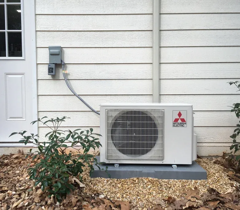 A ductless outdoor unit serviced at the side of a home